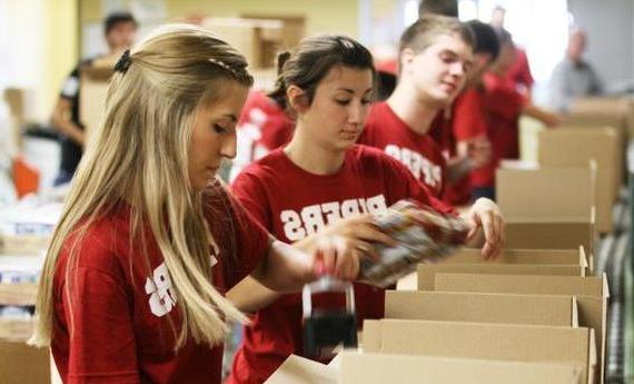三个体育博彩app的学生穿着红色的“piper”衬衫，一边做志愿者一边用胶带粘纸箱